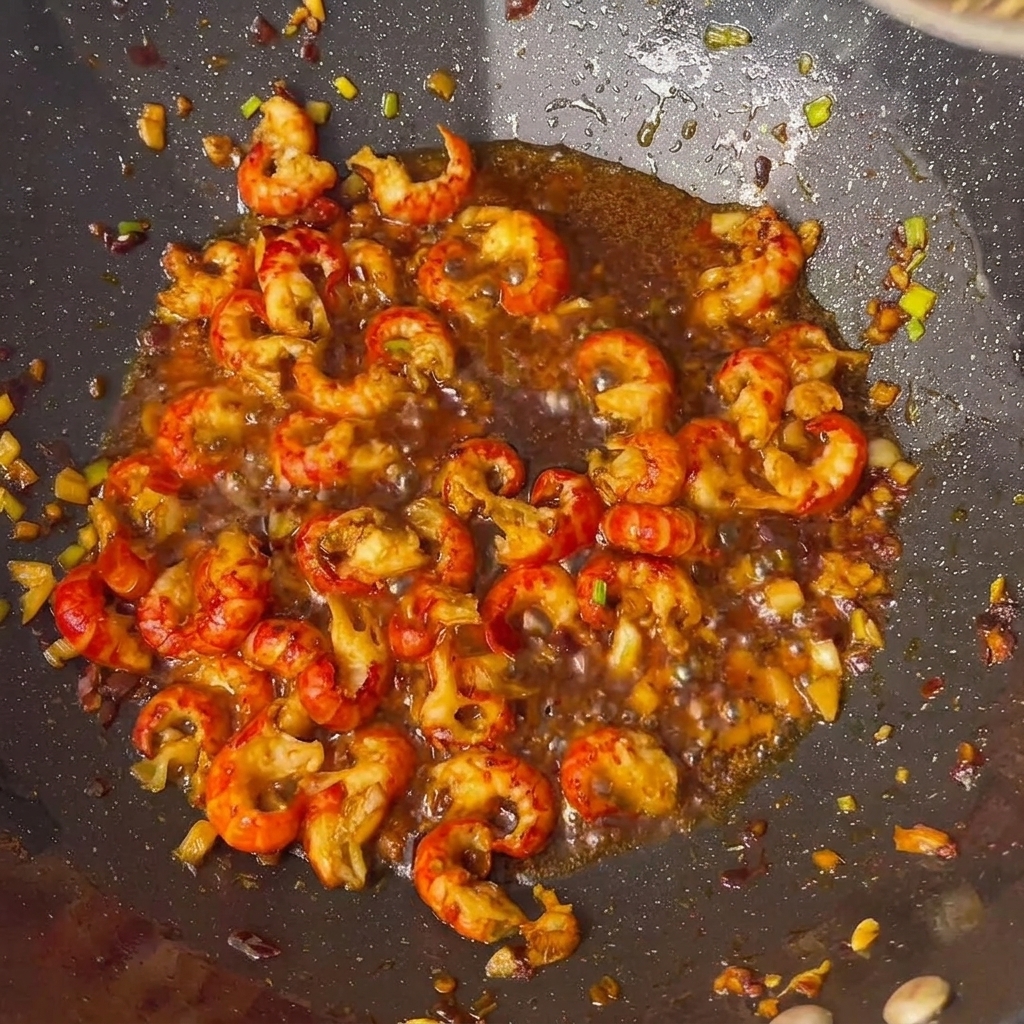 I gamberi conditi con salse e spezie nel wok.