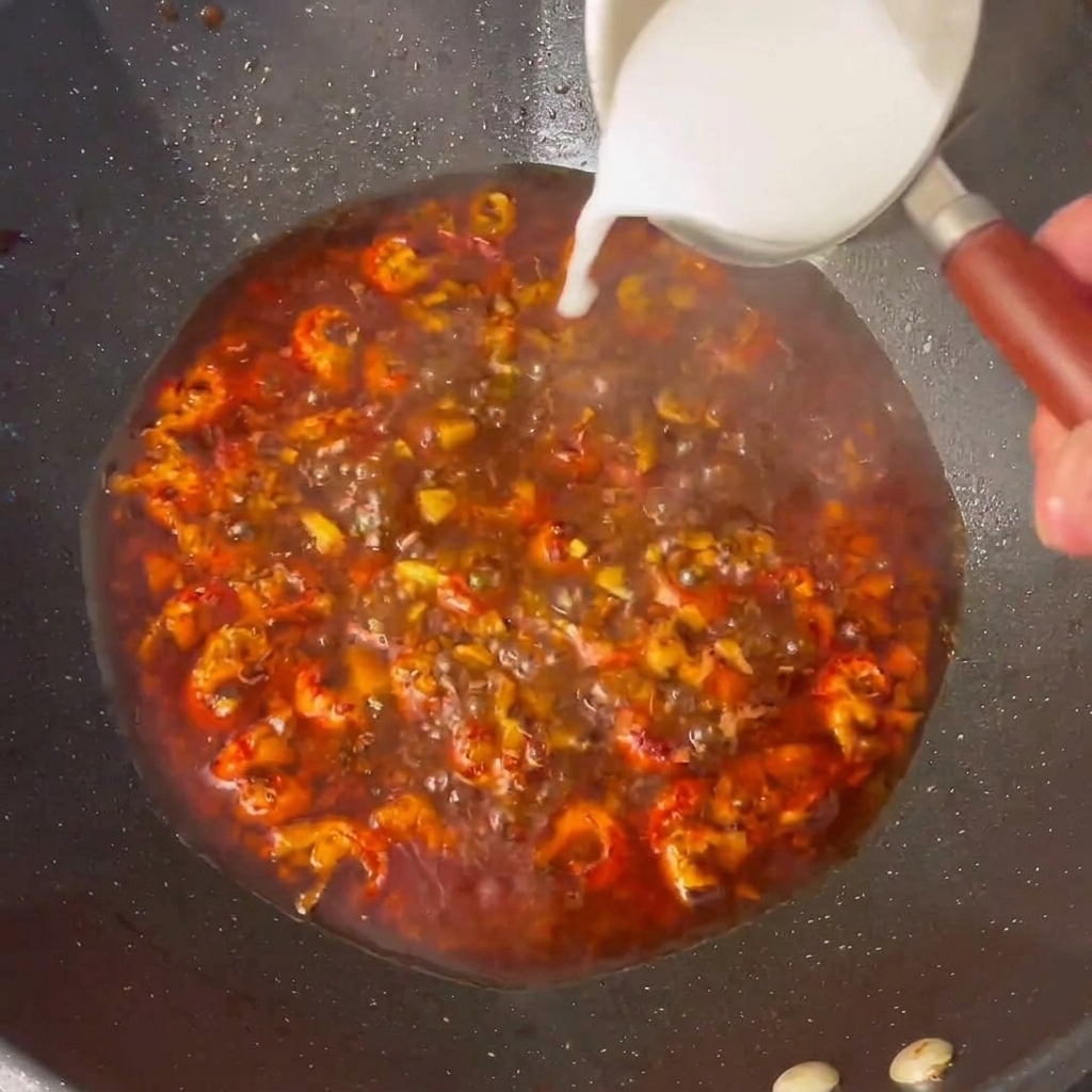 Amido di mais sciolto aggiunto alla salsa che sobbolle nel wok.