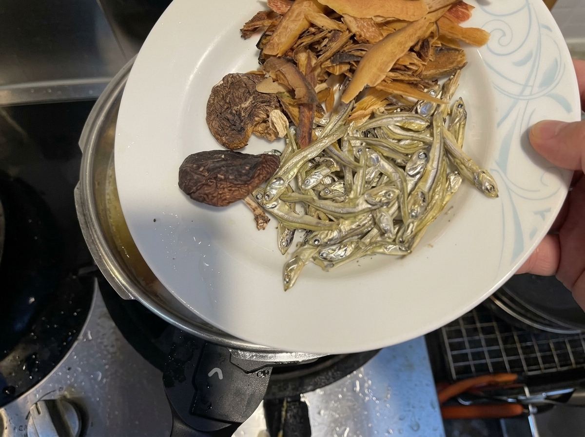 Pesce essiccato, funghi shiitake e fiocchi di pesce versati nel brodo.