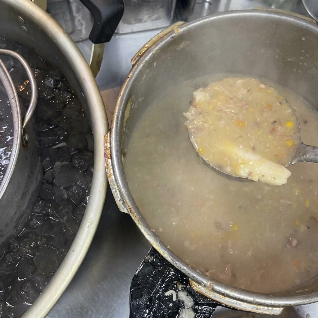 Un mestolo che solleva brodo denso e torbido accanto a una pentola posta in un bagno di ghiaccio.