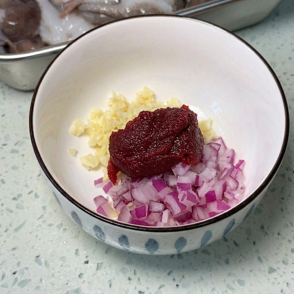 Unampia padella di metallo con fette di carne in scatola, würstel e cubetti di tofu disposti ordinatamente.