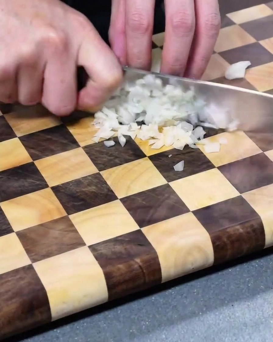 Pezzi di cipolla bianca finemente tritata su un tagliere di legno.
