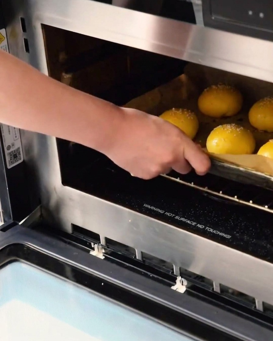 Teglia di panini crudi al sesamo pronti per essere infornati.