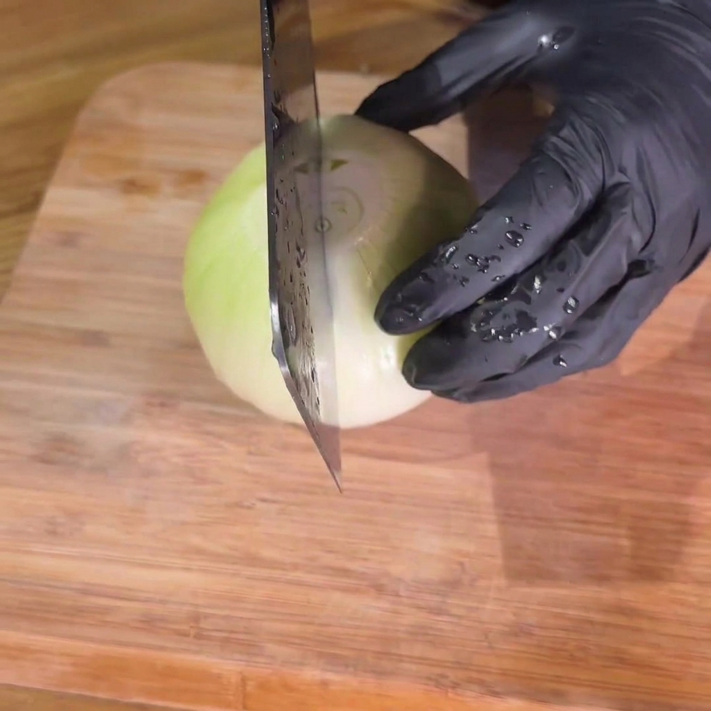 Cipolle tagliate con cura in strisce uniformi su un tagliere di legno.