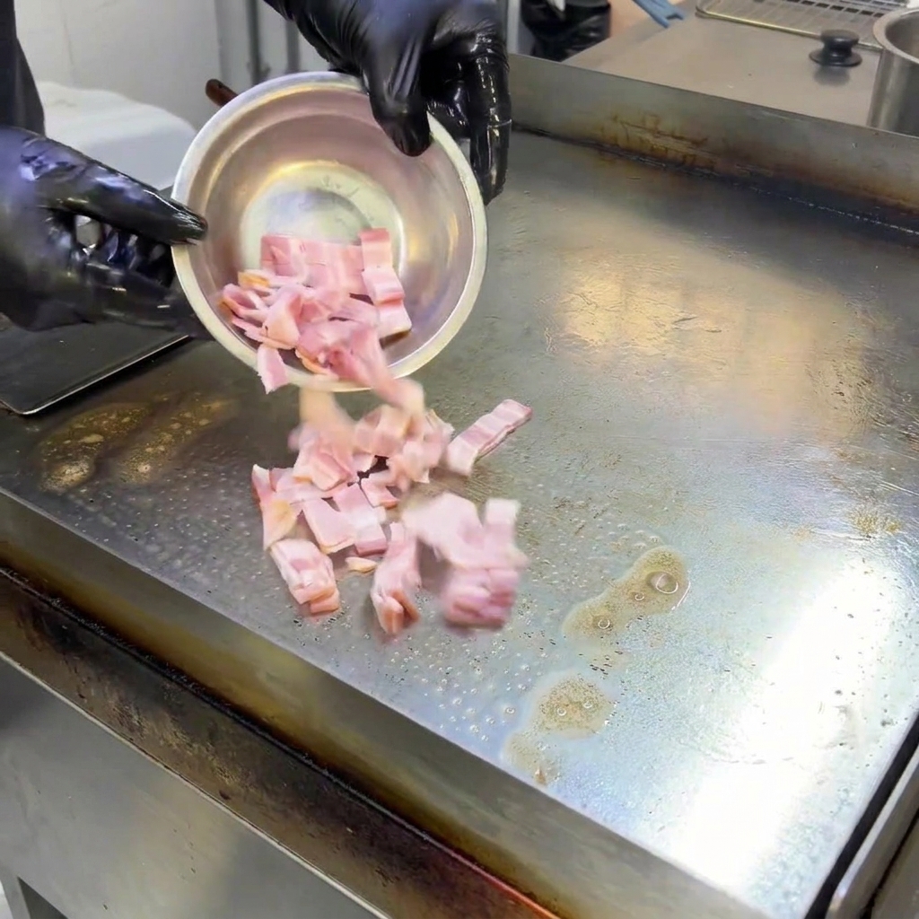 Pezzetti di pancetta che sfrigolano e friggono su una piastra calda, rilasciando grasso.