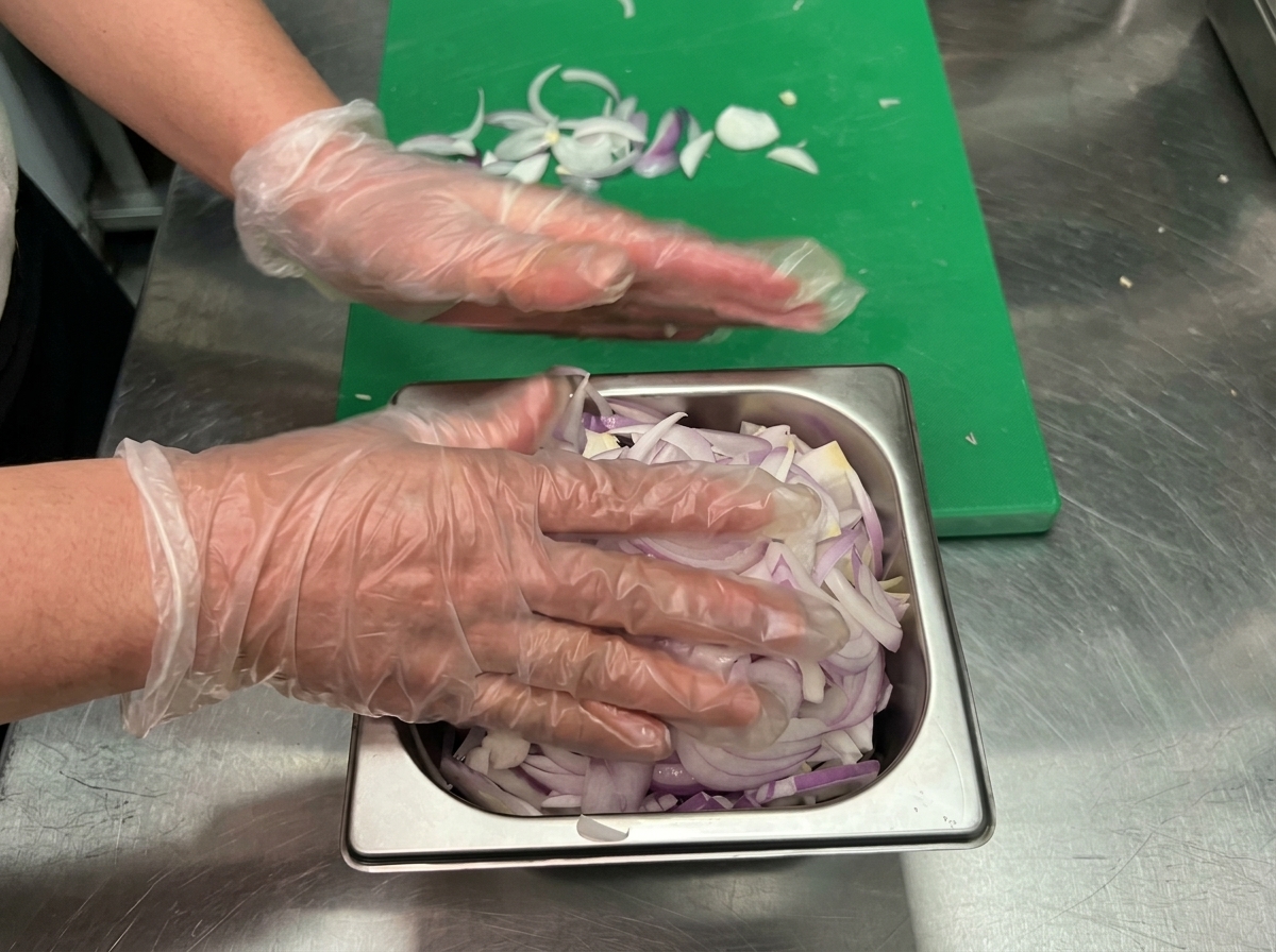 Cipolle rosolate in padella con laggiunta di vino rosso e olio doliva in fase di mescolatura.