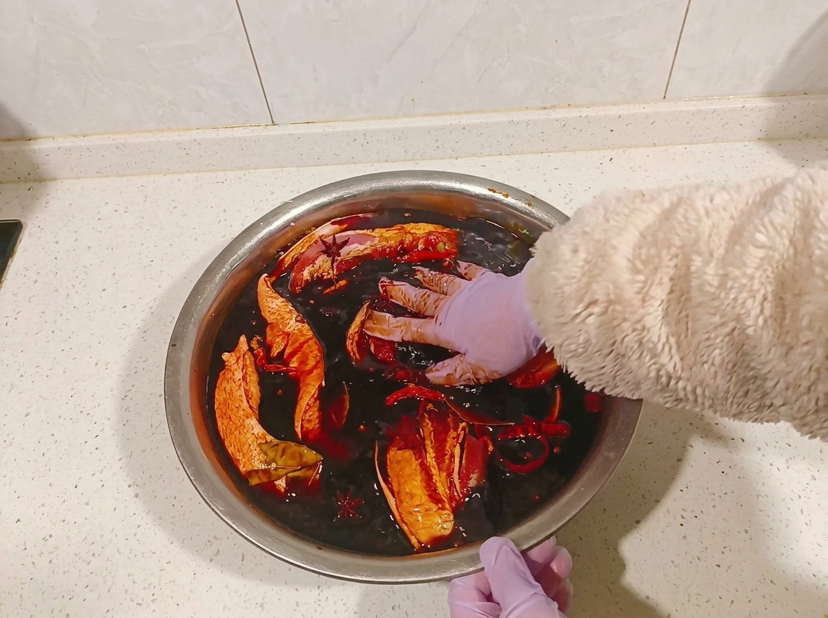 Mani che girano i pezzi di pancetta nella marinata scura.