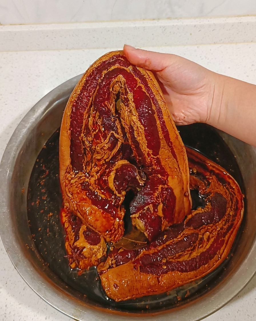 Pezzo di pancetta marinata sciacquato sotto un filo dacqua calda.