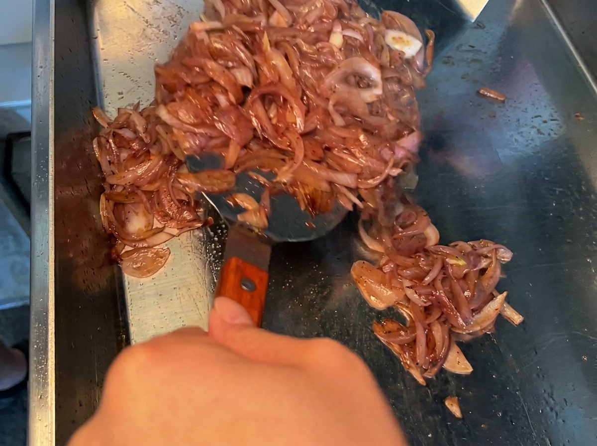 Marinata di salsa di soia versata su pezzi di pancetta cruda in una ciotola di metallo.