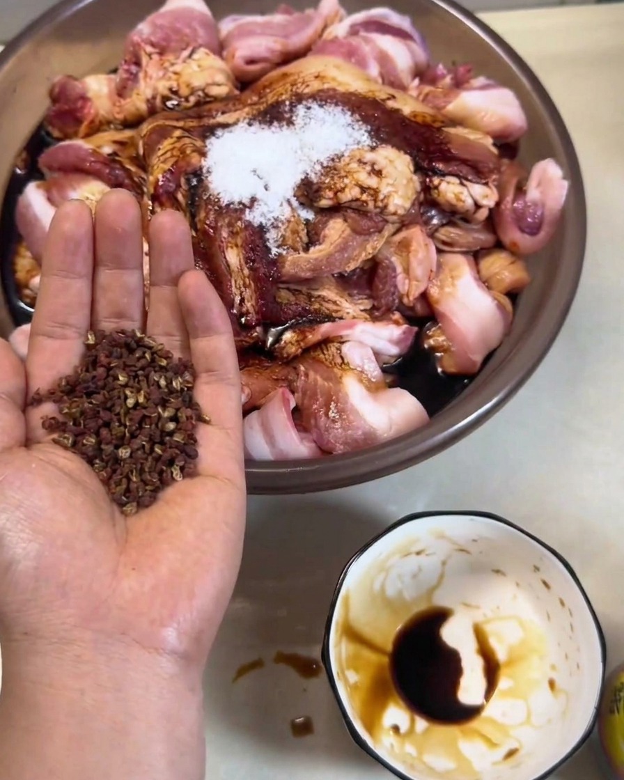 Strisce di pancetta marinata appese a ganci metallici su una rastrelliera allaperto.