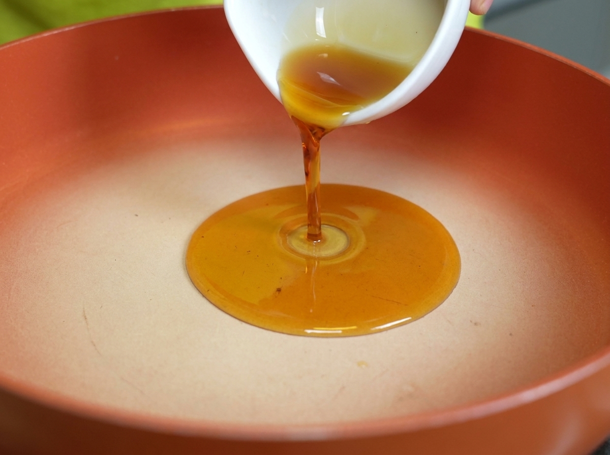 Olio di sesamo dorato versato in una padella pulita e calda.