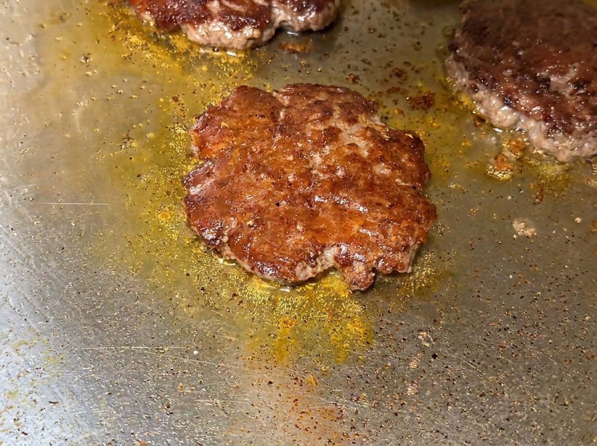 Dettaglio del formaggio fuso che copre gli hamburger scottati sulla piastra.