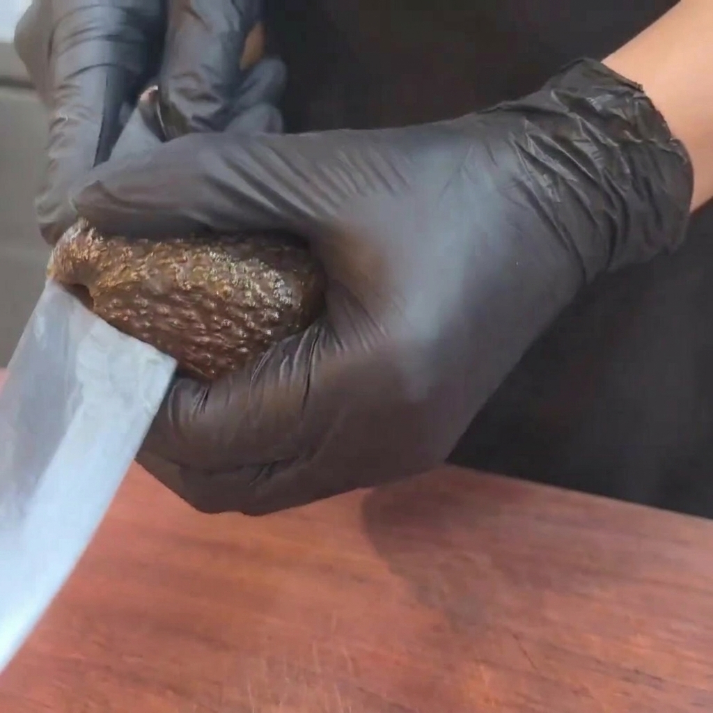 Un avocado maturo tagliato a metà con un coltello su un tagliere in legno.