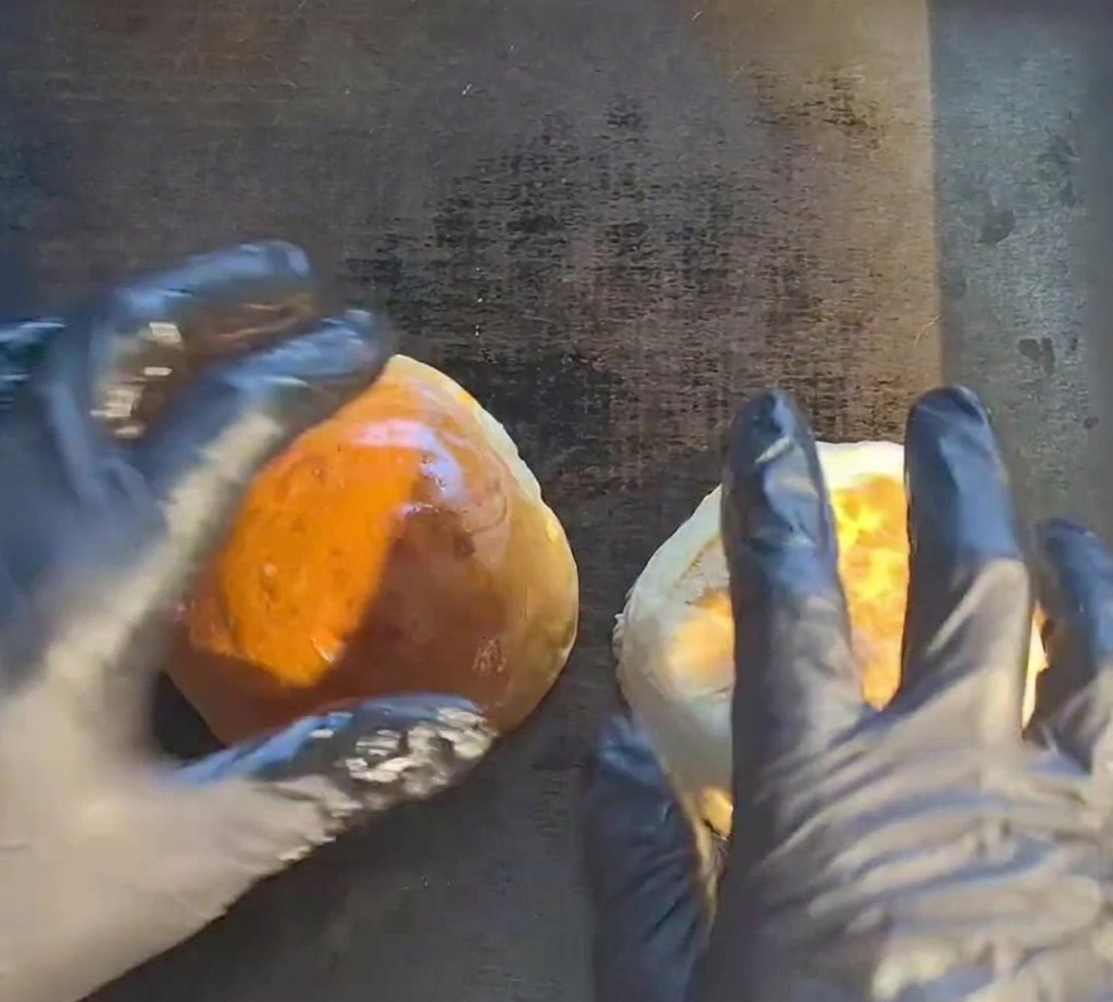 Un burger di manzo crudo che sfrigola su una piastra rovente.