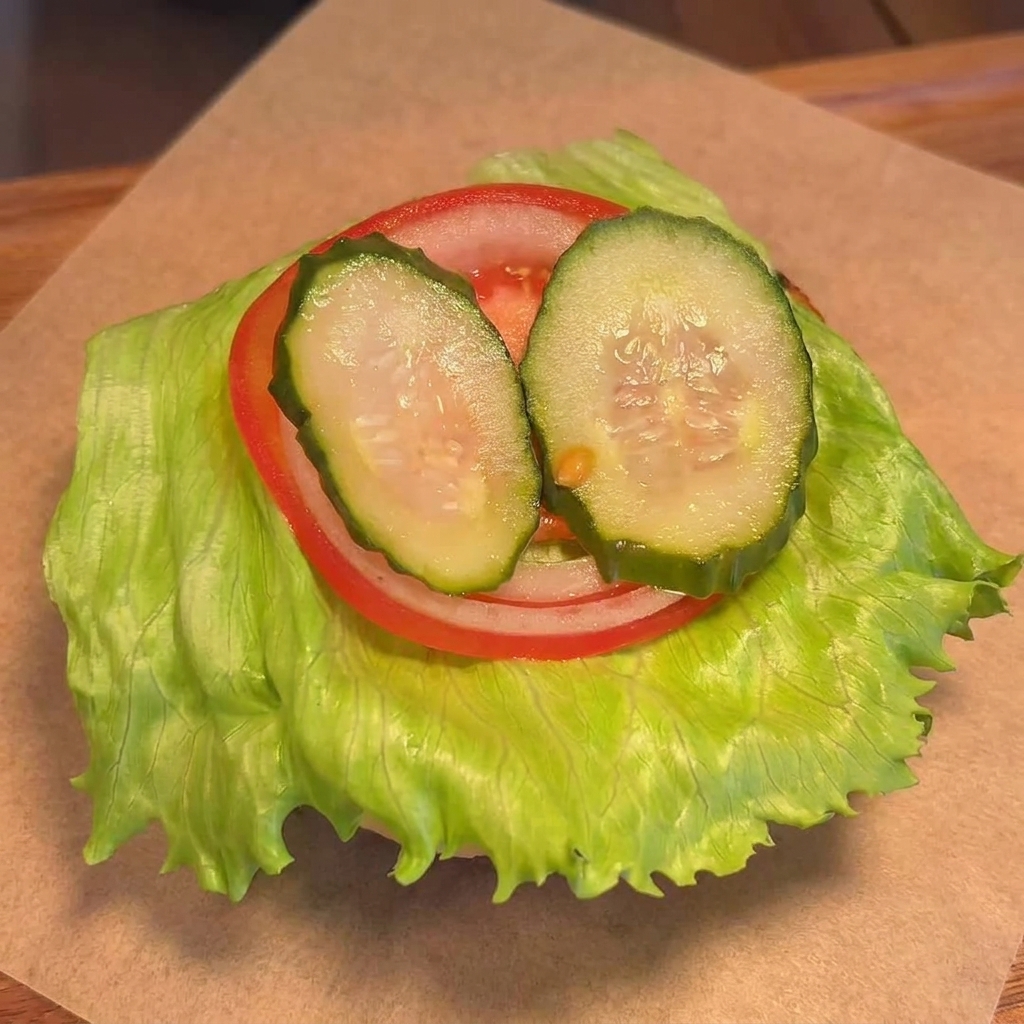 Hamburger di manzo con formaggio fuso posizionato sul pane con verdure.