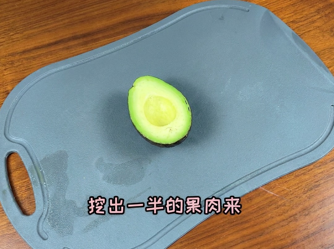 Un avocado tagliato a metà su un tagliere, pronto per essere affettato.