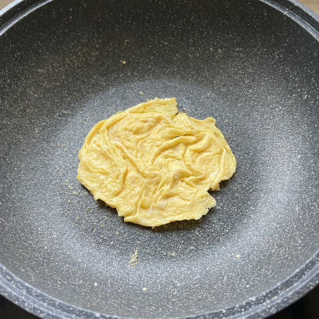 Una fetta di formaggio che si scioglie sopra la frittatina in padella.