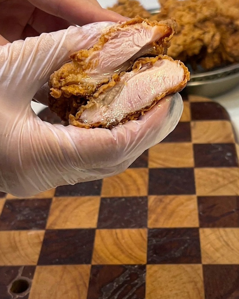 Un primo piano di un filetto di pollo fritto tagliato, che mostra la carne bianca e umida allinterno.