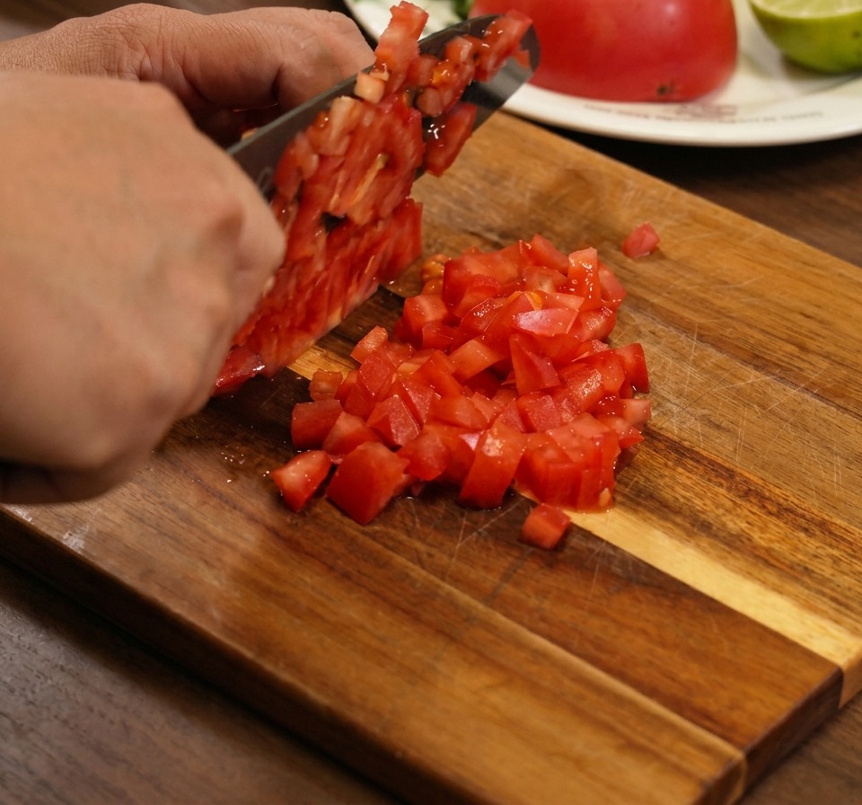 Primo piano di pomodori a cubetti, cipolla rossa e coriandolo mescolati insieme in una ciotola.