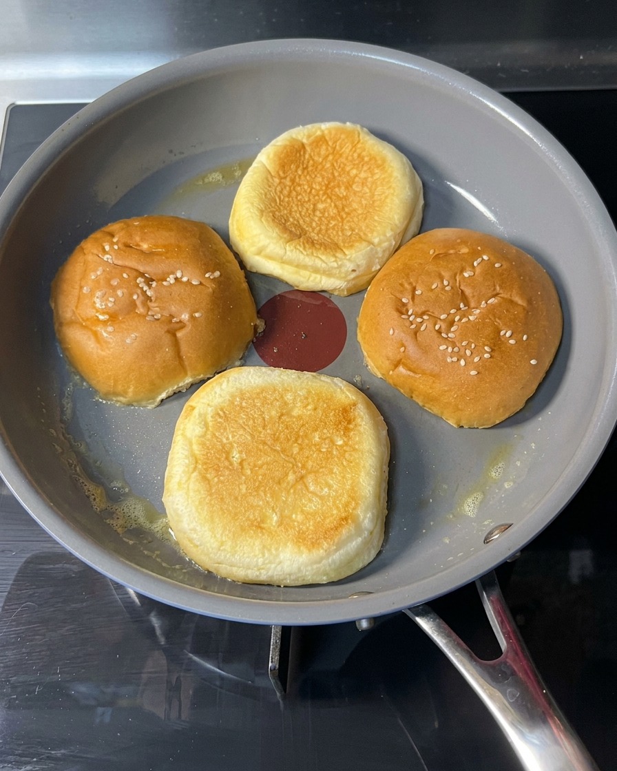 Una mano che gira un panino tostato in padella mostrando una superficie dorata.