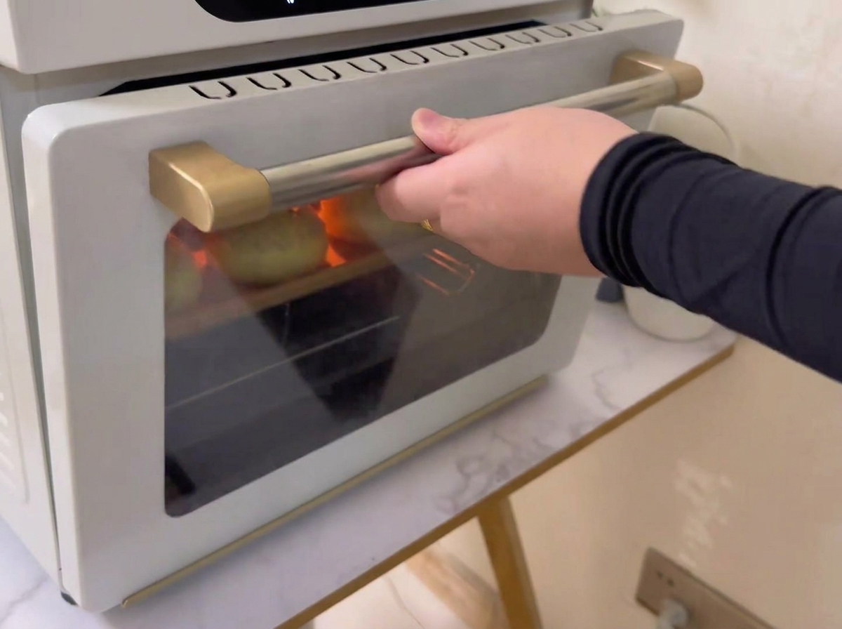 Una teglia riempita con panini ricoperti di sesamo che viene inserita in un forno.