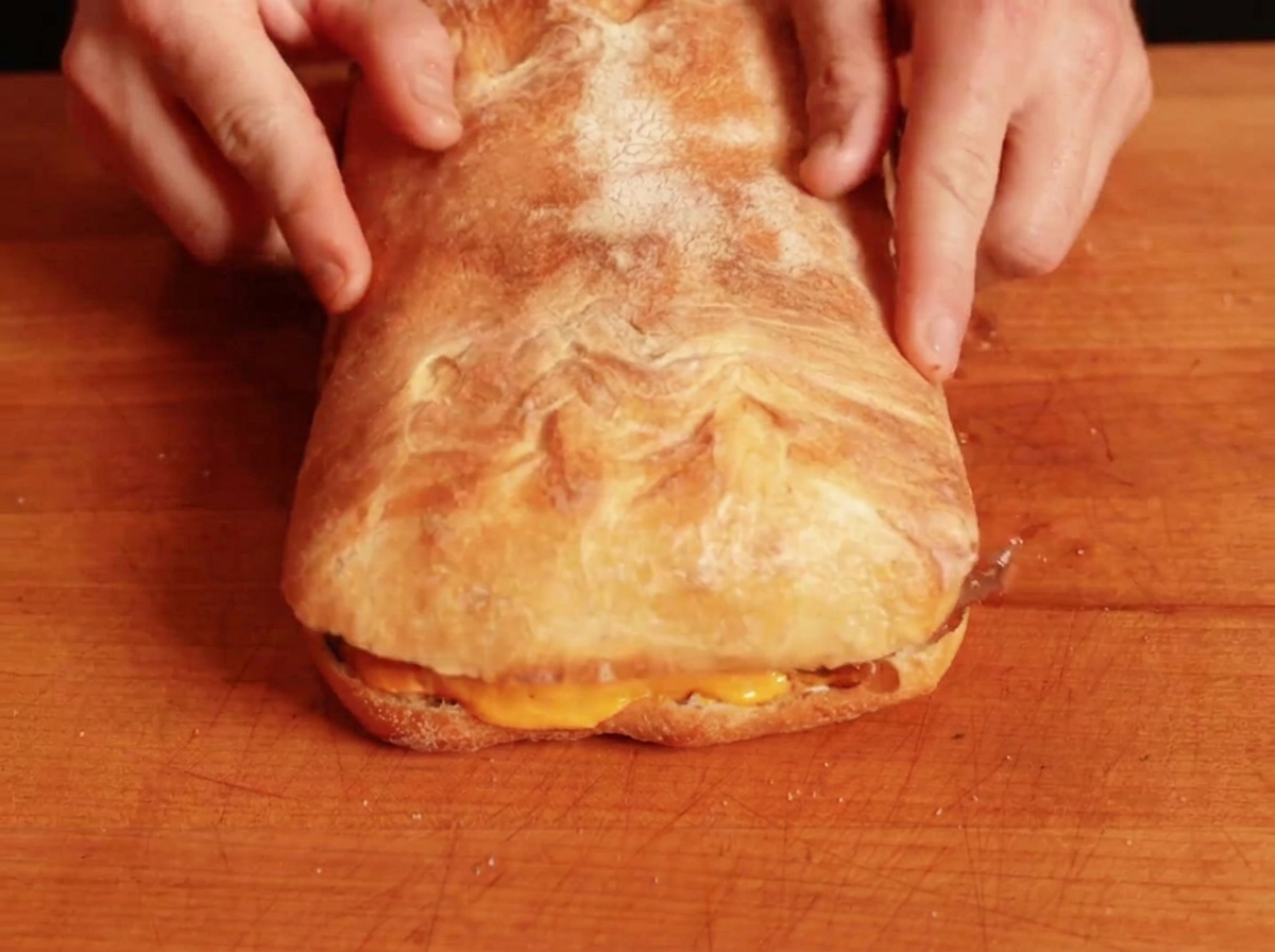 Il pezzo superiore di pane posizionato sopra il panino farcito per completare lassemblaggio.