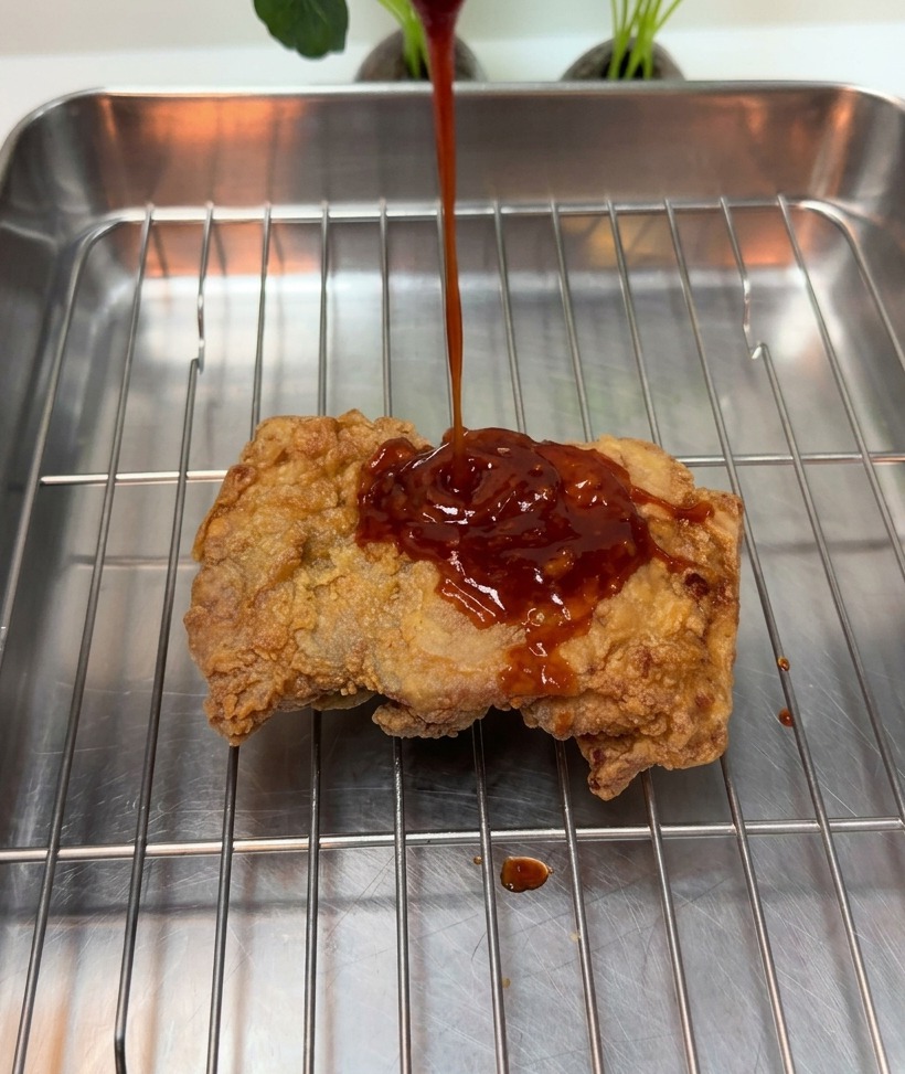 Salsa rossa densa versata su un pezzo di pollo fritto.