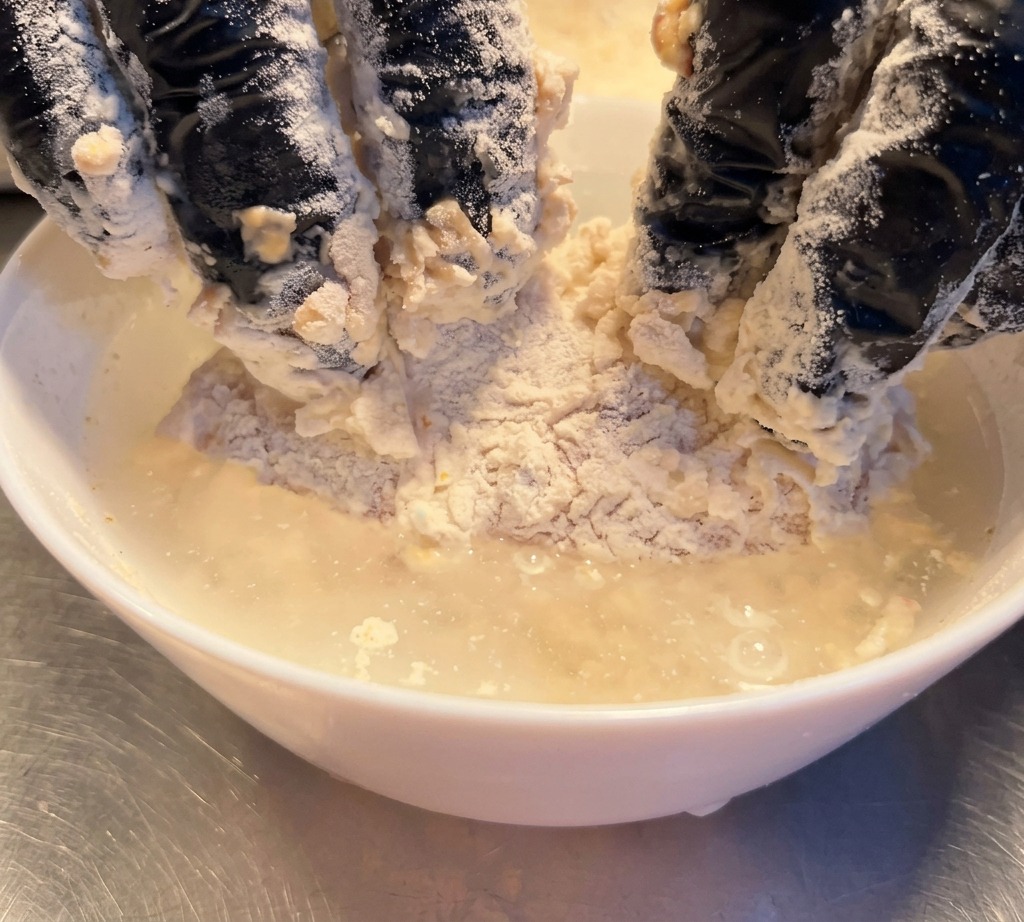 Pezzo di pollo infarinato immerso brevemente nellacqua.
