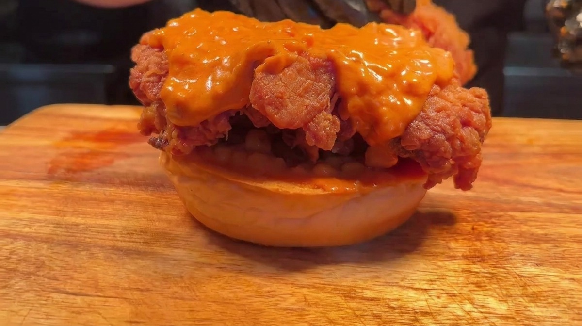 Assemblaggio del burger doppio con secondo strato di pollo.