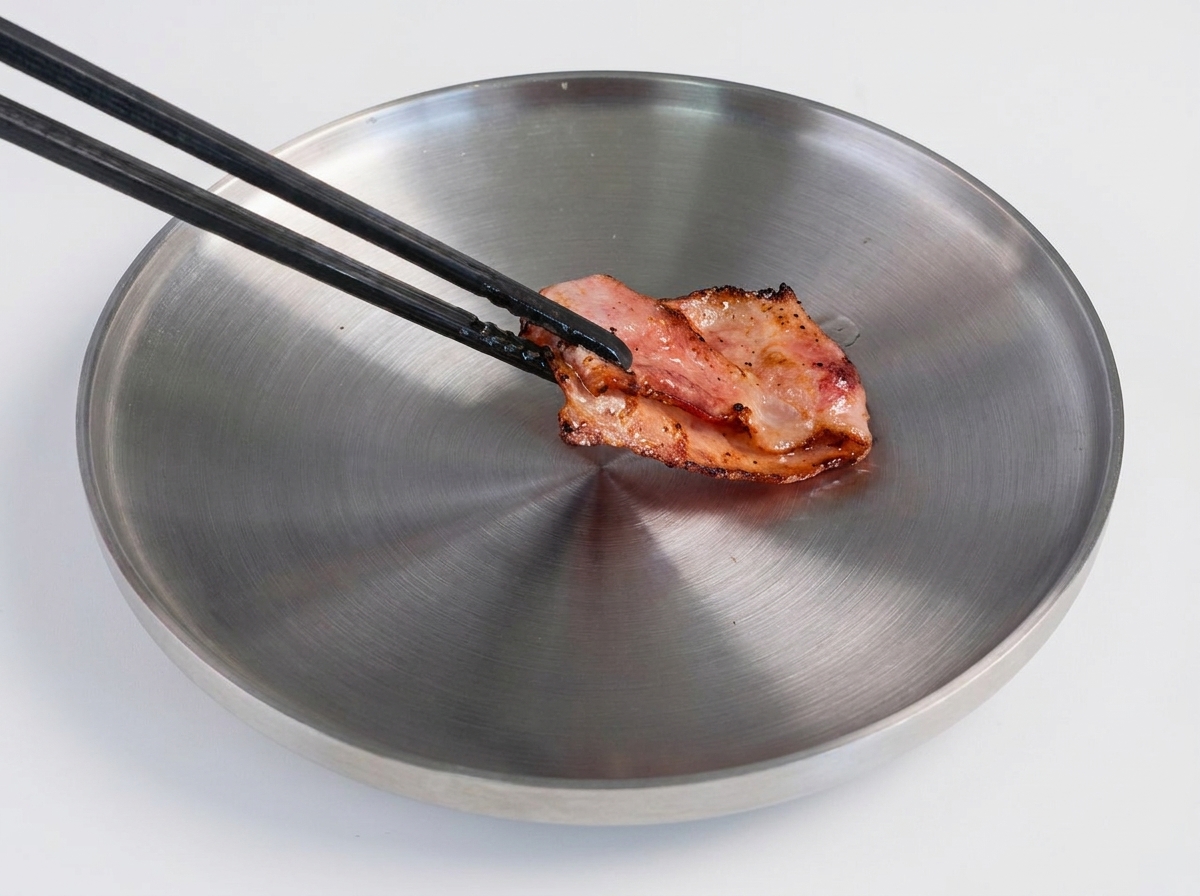 Una spatola che gira un hamburger di manzo rosolato in una padella calda.
