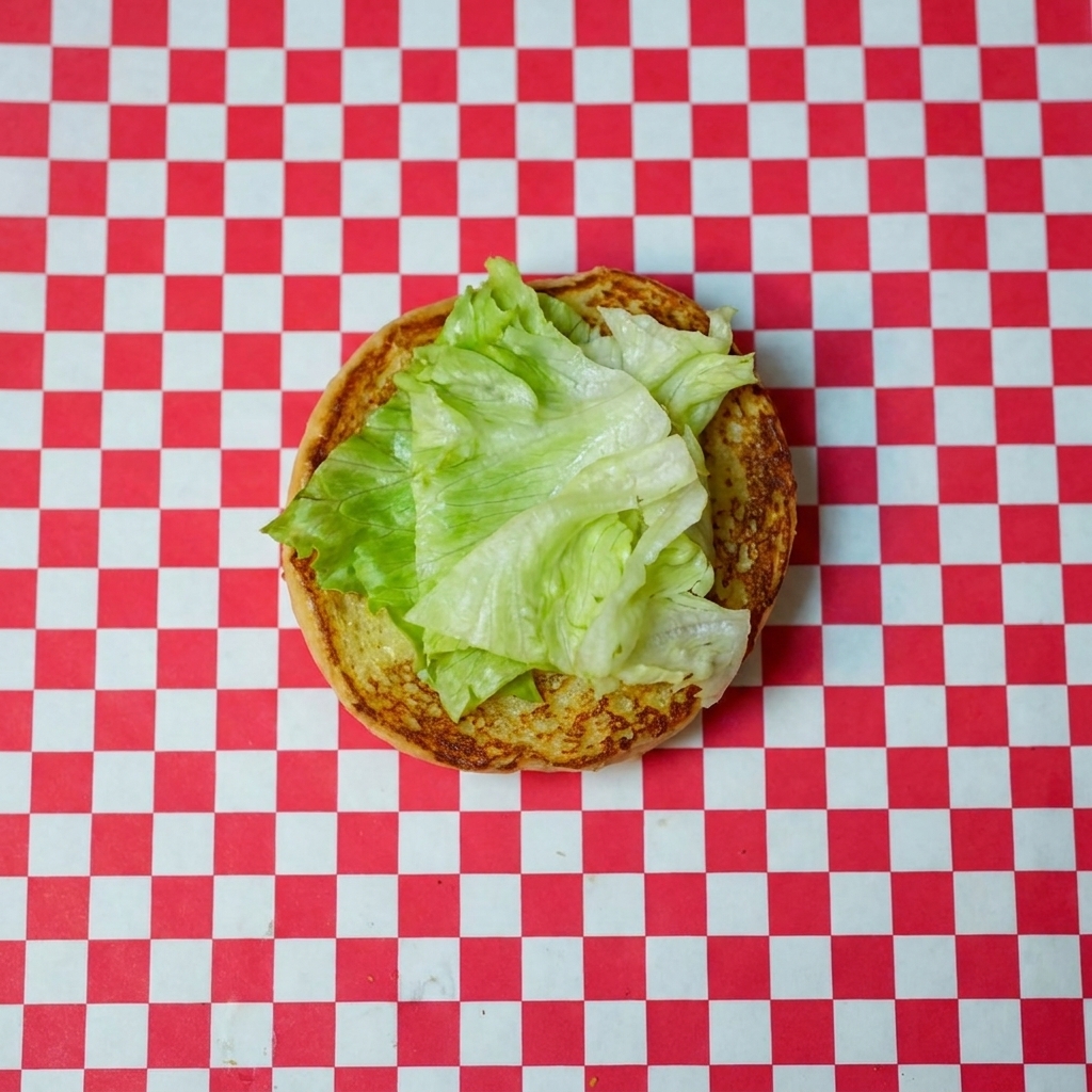 Lattuga fresca e una fetta di pomodoro vivace posizionate sul fondo del panino tostato.