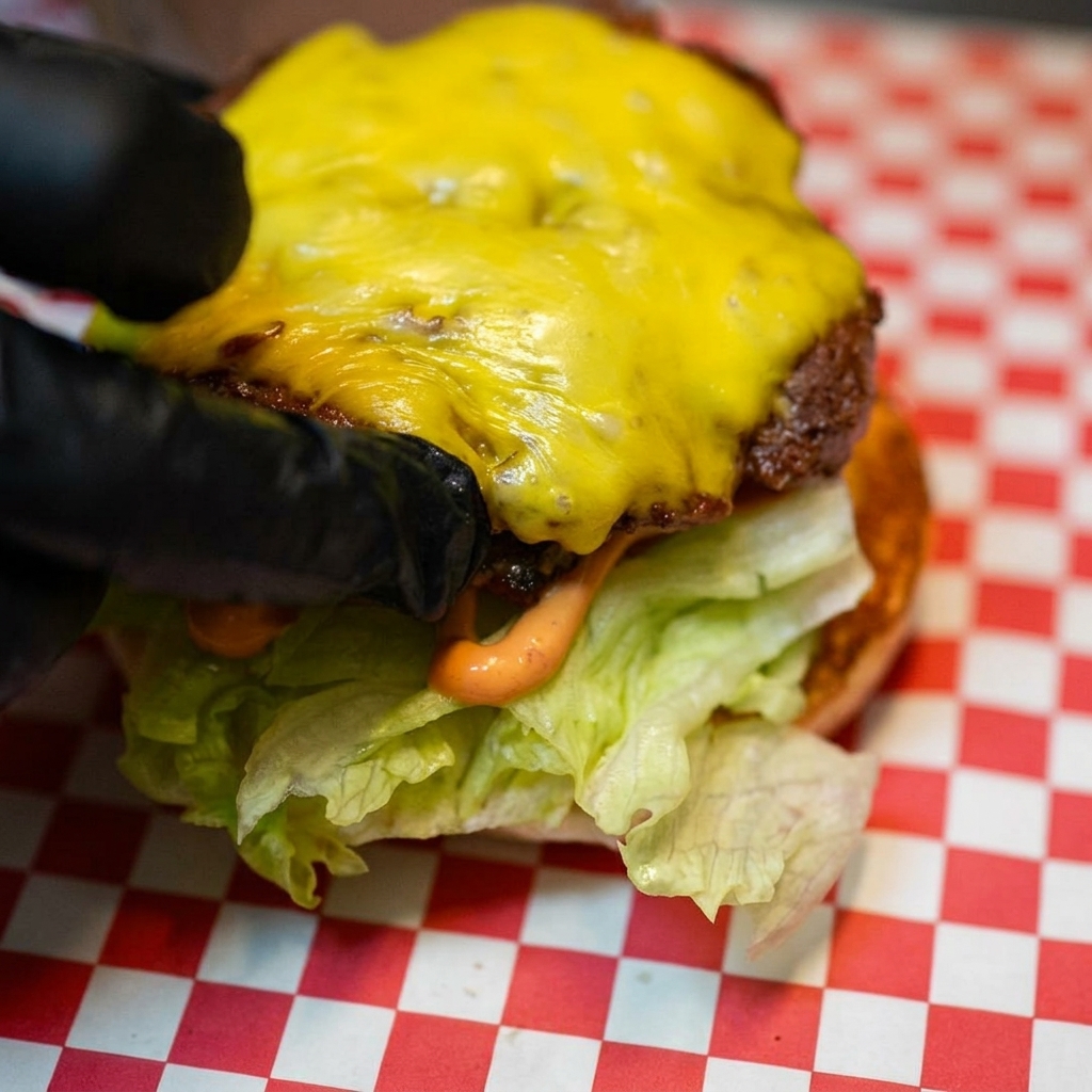 Lhamburger di manzo ricoperto di formaggio fuso posizionato sopra la base di lattuga e pomodoro.