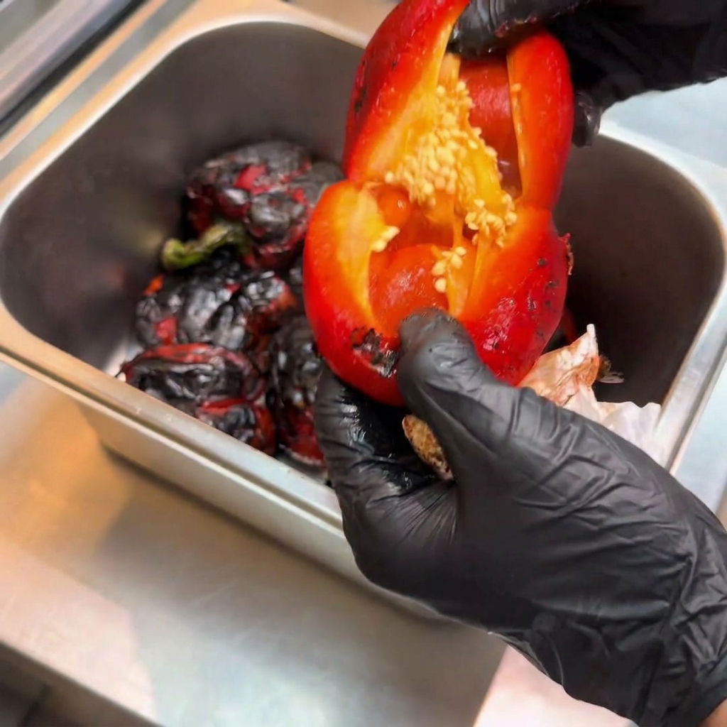 Peperone rosso arrostito pelato aperto per rivelare linterno con i semi che vengono rimossi.