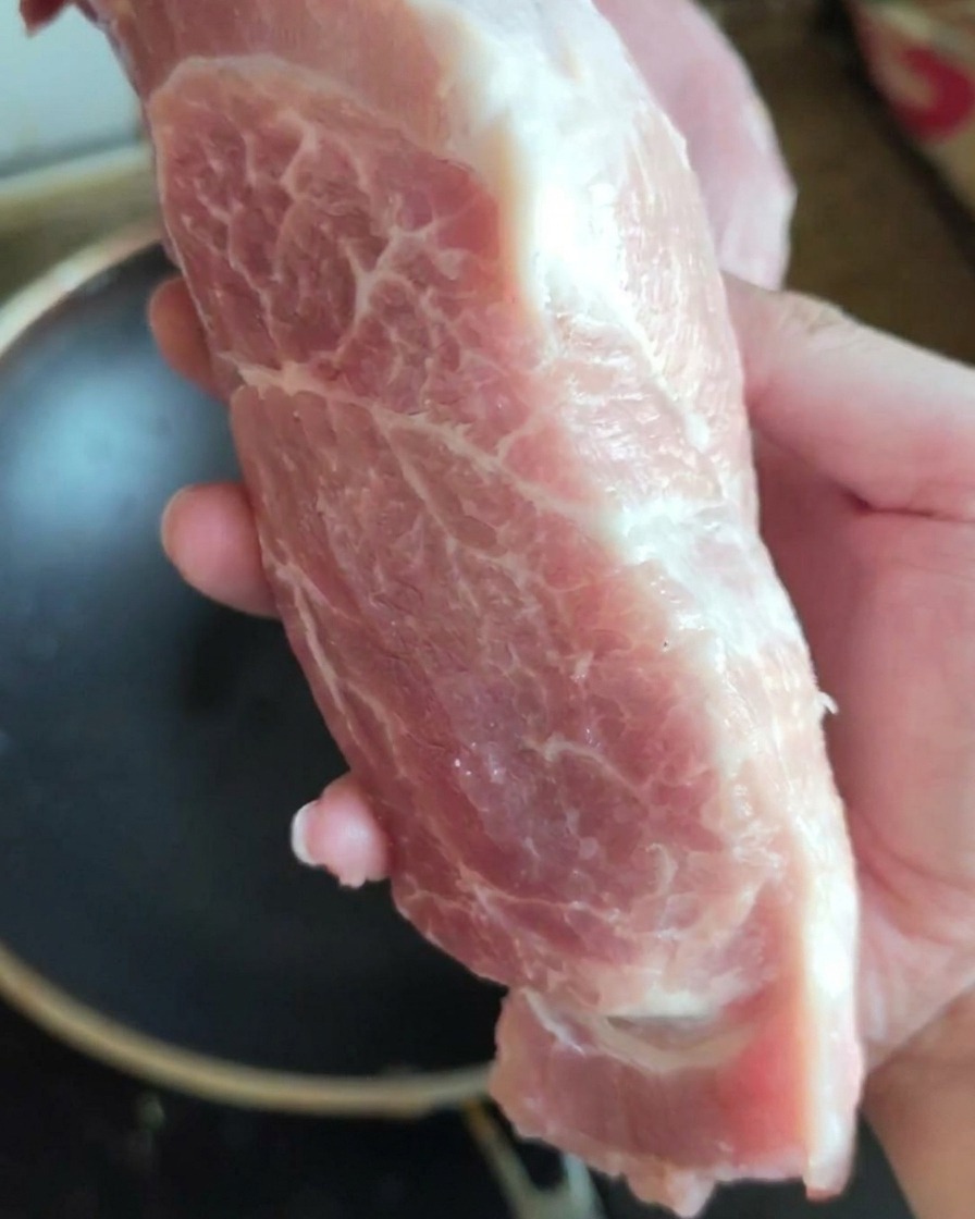 Un pezzo grande e fresco di spalla di maiale cruda mostrato alla fotocamera.
