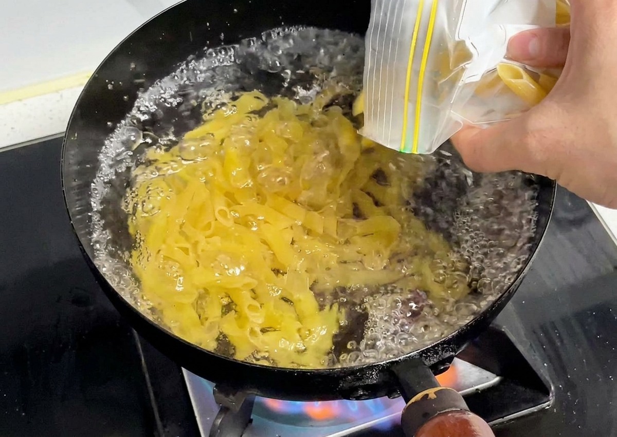 Penne secche versate in una pentola dacqua in ebollizione vivace.