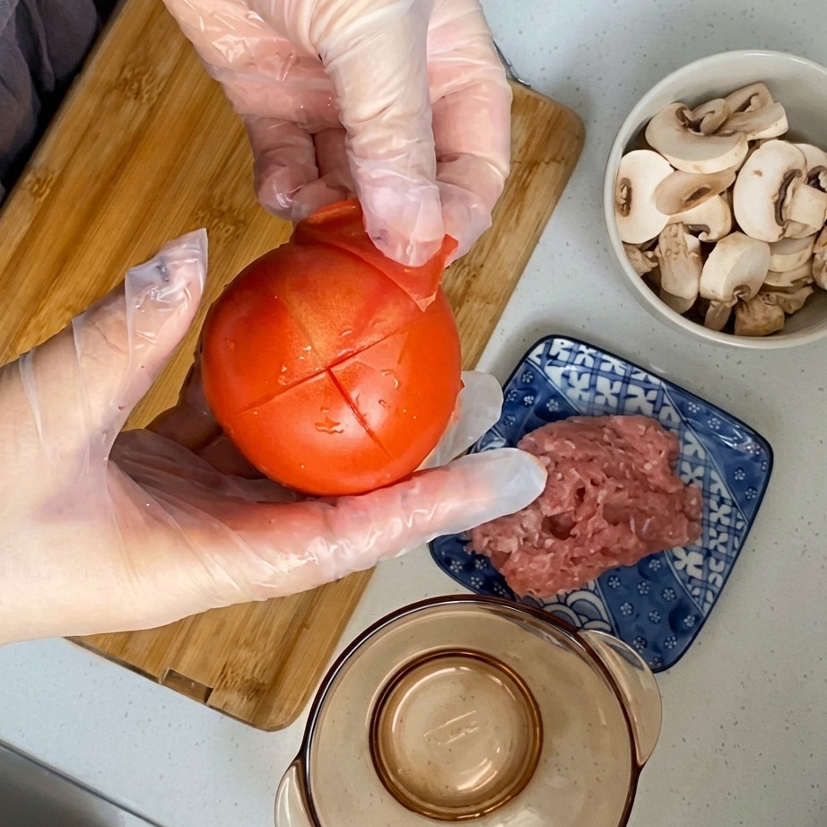 La buccia che viene tolta da un pomodoro sbollentato e inciso.