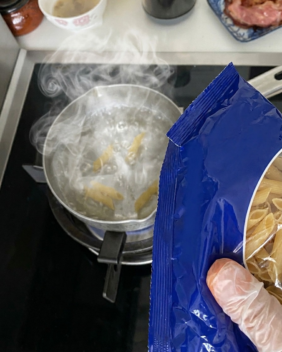 Penne secche versate da una confezione in una pentola dacqua bollente.