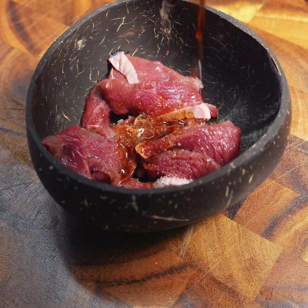 Salsa scura versata sul manzo affettato in una ciotola.