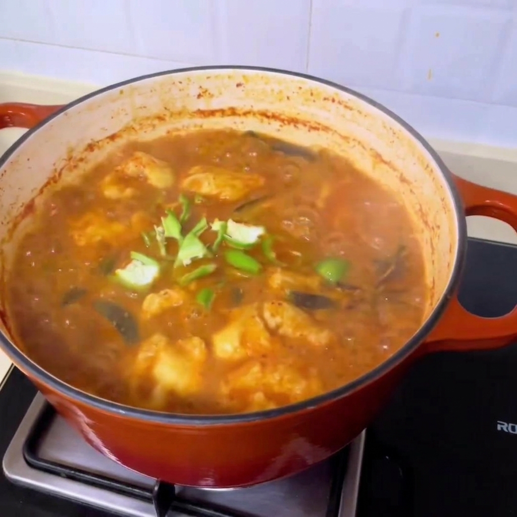 Fette di peperoncino verde fresco sparse sopra la ricca zuppa di vongole in stile coreano che bolle.