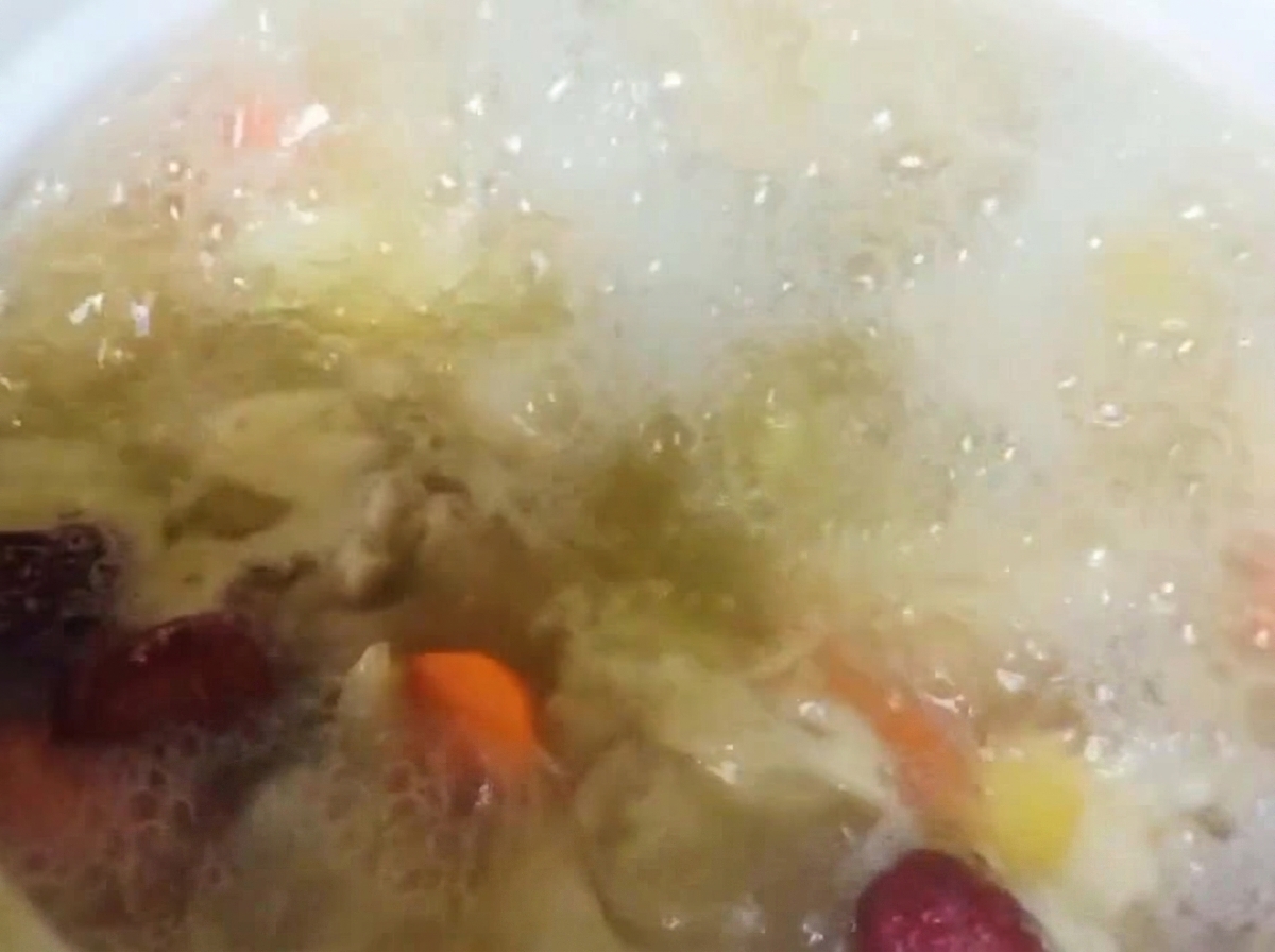 Grani di pepe di Sichuan aggiunti allo stufato di pollo e verdure in cottura.