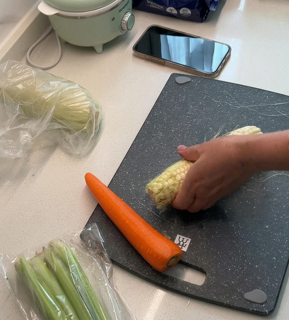 Chicchi di mais fresco tagliati dalla pannocchia su un tagliere, con le bucce e le barbe messe da parte.