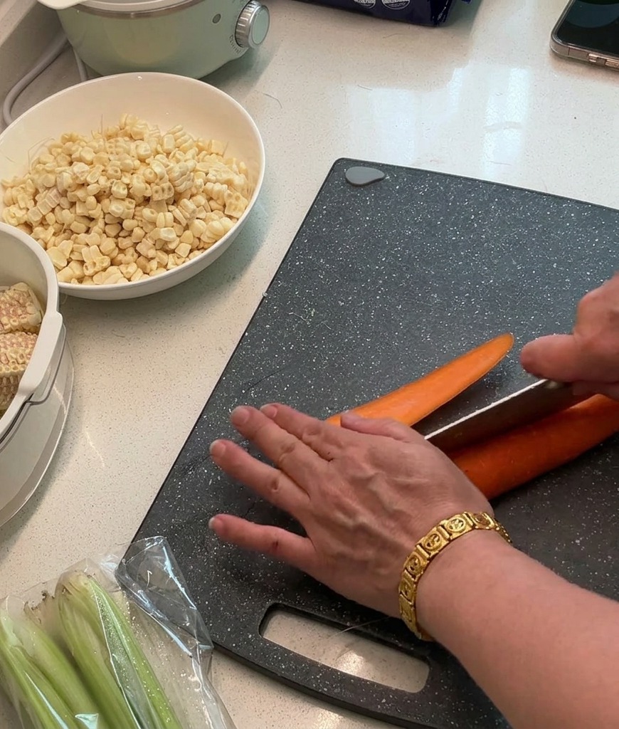 Carote fresche tagliate a cubetti piccoli e regolari su un tagliere scuro.