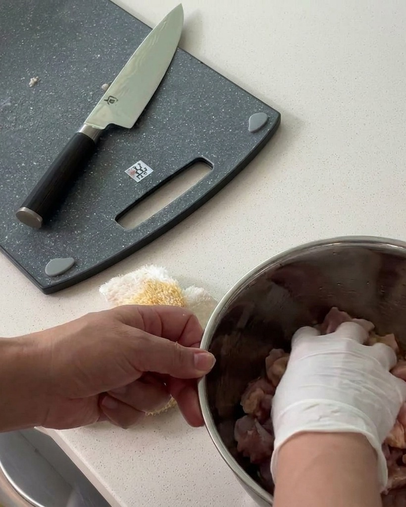 Pollo a cubetti mescolato con i condimenti in una ciotola di metallo.