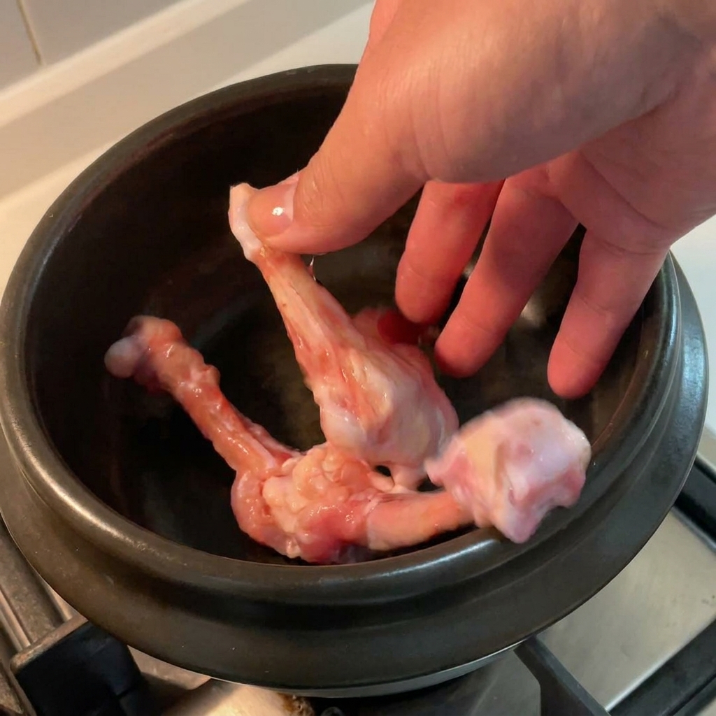 Ossa di pollo crude disposte allinterno di una pentola in ceramica nera.