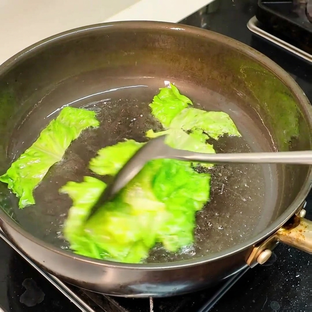 Foglie di lattuga saltate in padella con olio caldo.