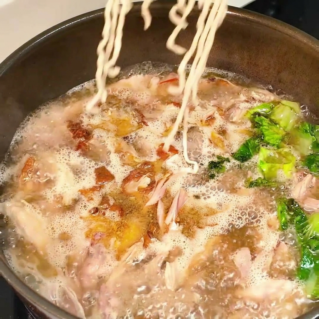 Noodles aggiunti in padella nel brodo bollente.