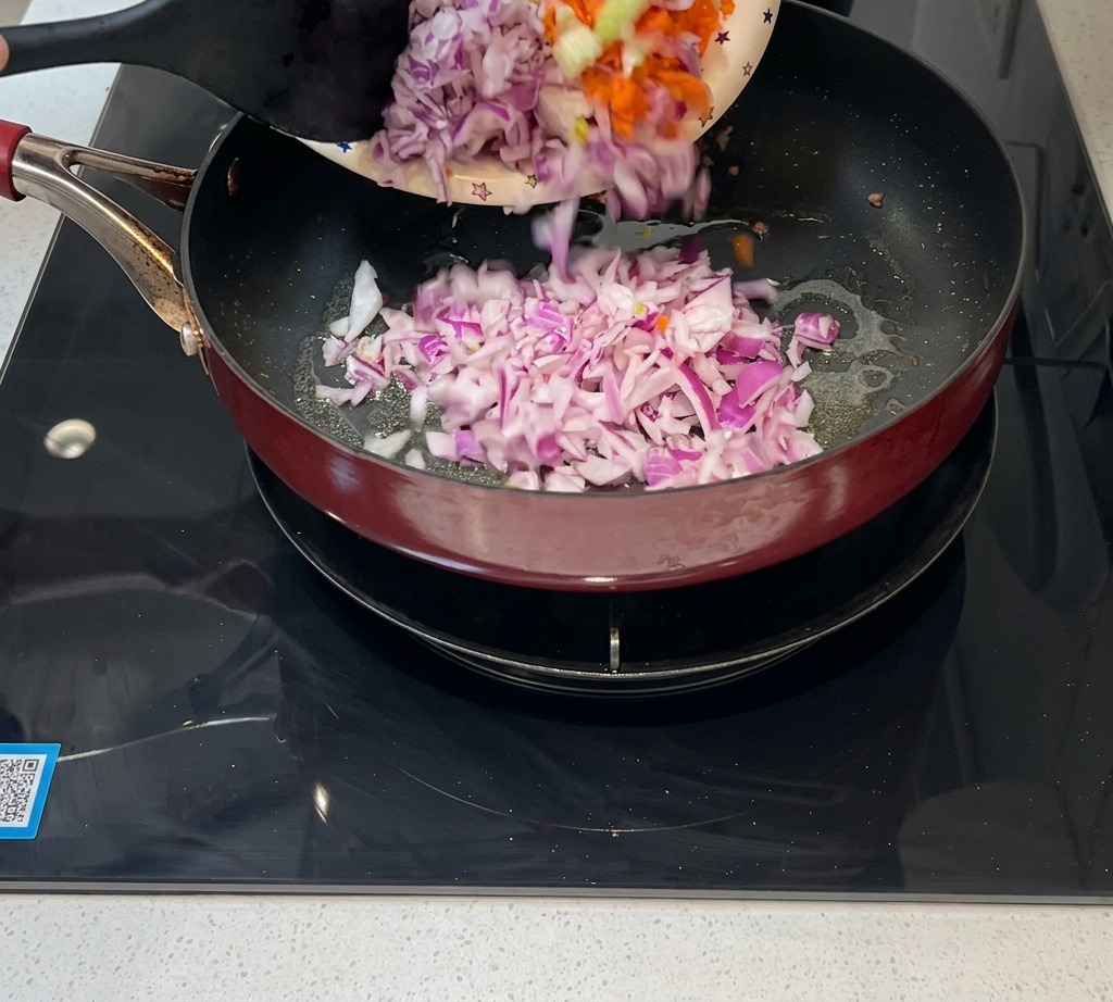 Cipolla, carota e sedano tritati versati in padella per il soffritto.