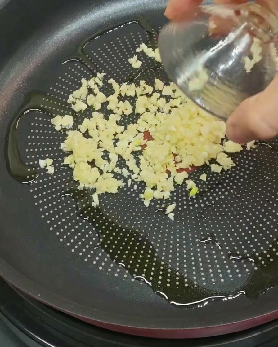 Aglio tritato versato in una padella con olio doliva.
