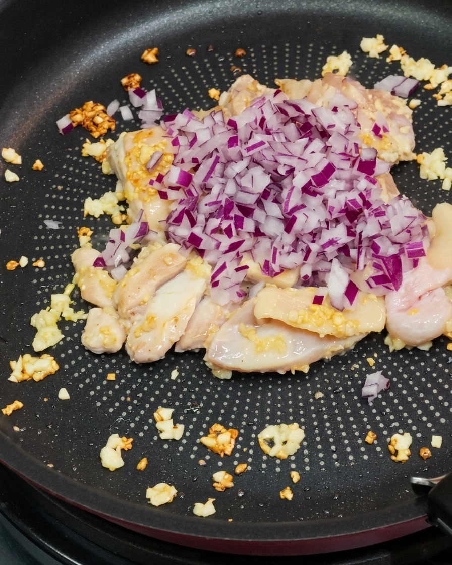 Cipolla rossa versata in padella con il pollo rosolato.