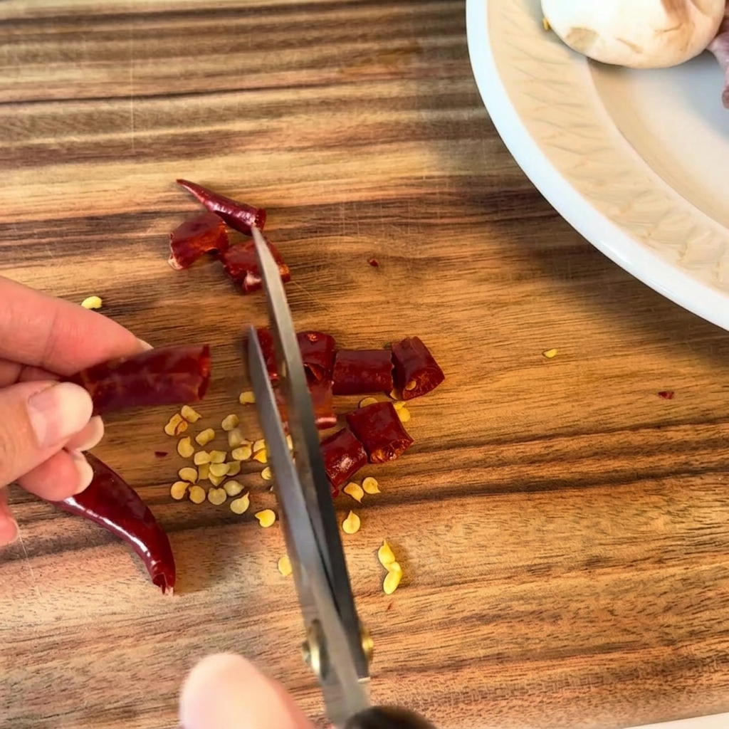 Peperoncini secchi tagliati a pezzetti con le forbici da cucina.